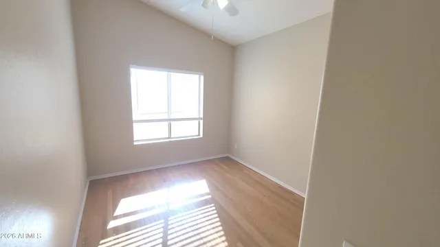 an empty room with windows and chandelier fan