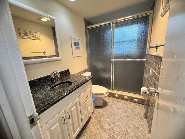 a bathroom with a granite countertop sink toilet and shower