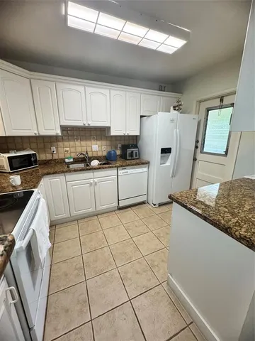 a kitchen with a refrigerator sink and cabinets