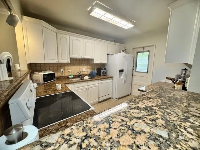a kitchen with stainless steel appliances granite countertop a stove a sink and a microwave