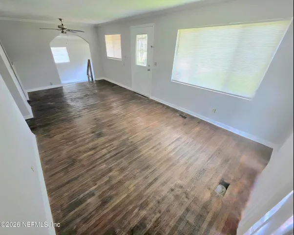 a view of an empty room with wooden floor and a window