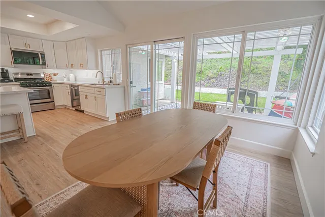 a living room with stainless steel appliances furniture a large window and a kitchen view
