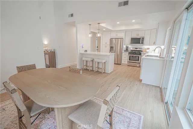 a kitchen with stainless steel appliances a refrigerator a stove a sink dishwasher and white cabinets with wooden floor