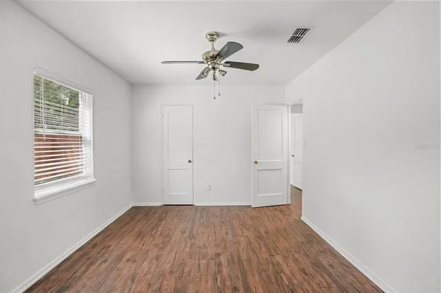 a view of a room with wooden floor and a ceiling fan