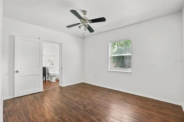 a view of empty room with wooden floor and ceiling fan