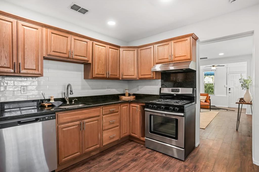 720 West Webster Avenue Winter Park, FL 32789 - Photo 5 of 22 a kitchen with stainless steel appliances granite countertop a stove a sink dishwasher and a microwave oven with wooden cabinets