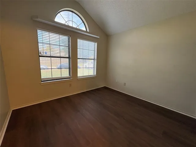 an empty room with wooden floor a exposed radiator and a window