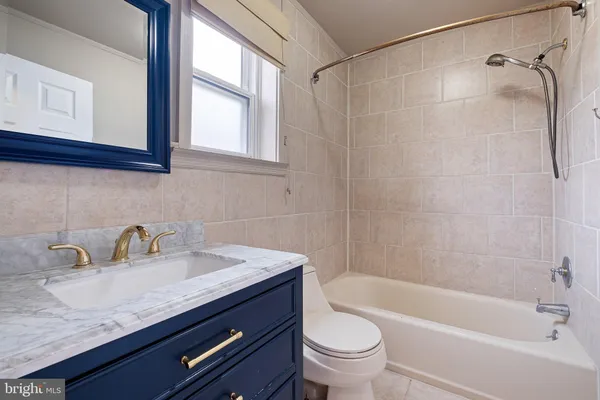 a bathroom with a granite countertop sink a toilet and shower