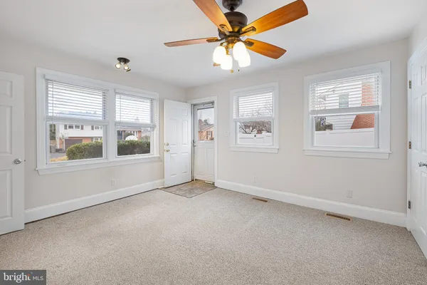 an empty room with windows and chandelier fan