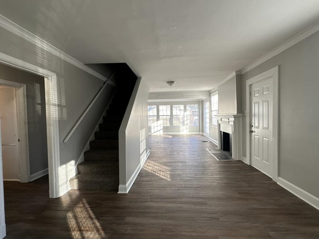 994 Hale Road Memphis, TN 38116 - Photo 7 of 24 Unfurnished living room featuring dark wood-type flooring, ornamental molding, stairs, and a fireplace
