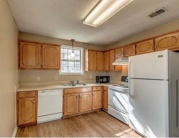 a white refrigerator freezer sitting inside of a kitchen with stainless steel appliances granite countertop a refrigerator a sink a stove a microwave and cabinets