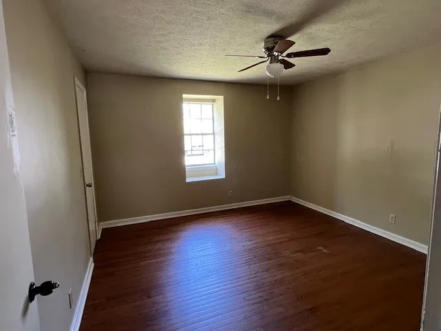 a view of an empty room with a window and wooden floor