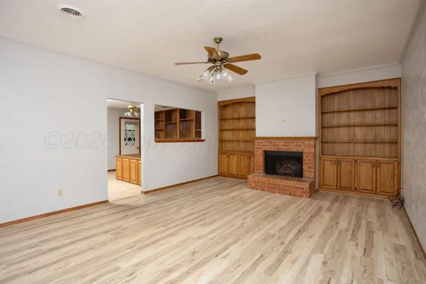 a view of a livingroom with an empty kitchen and a fireplace