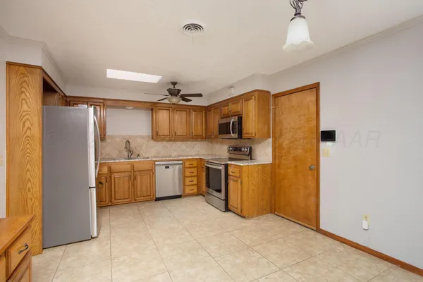 a view of a kitchen with a sink and dishwasher a refrigerator with white cabinets