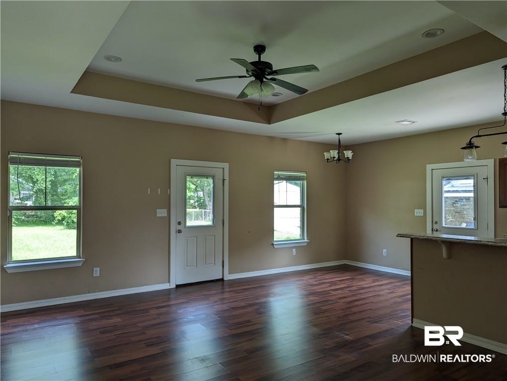 659 Bond Street Mobile, AL 36607 - Photo 3 of 10 Unfurnished living room with dark hardwood / wood-style floors, ceiling fan with notable chandelier, and a raised ceiling