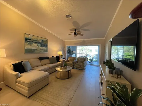 a living room with furniture a flat screen tv and a large window