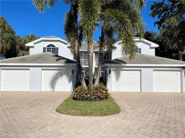 a view of a white house with a yard and palm trees