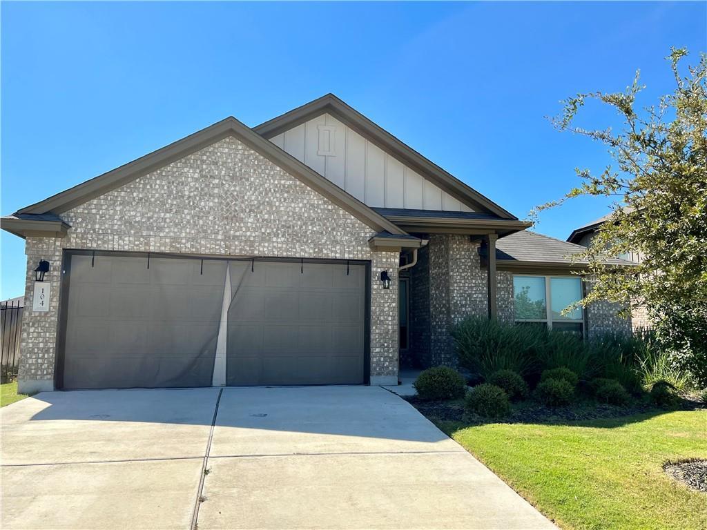 104 Beech Creek Lane Leander, TX 78641 - Photo 1 of 13 View of front of house with brick siding, board and batten siding, concrete driveway, an attached garage, and a front lawn