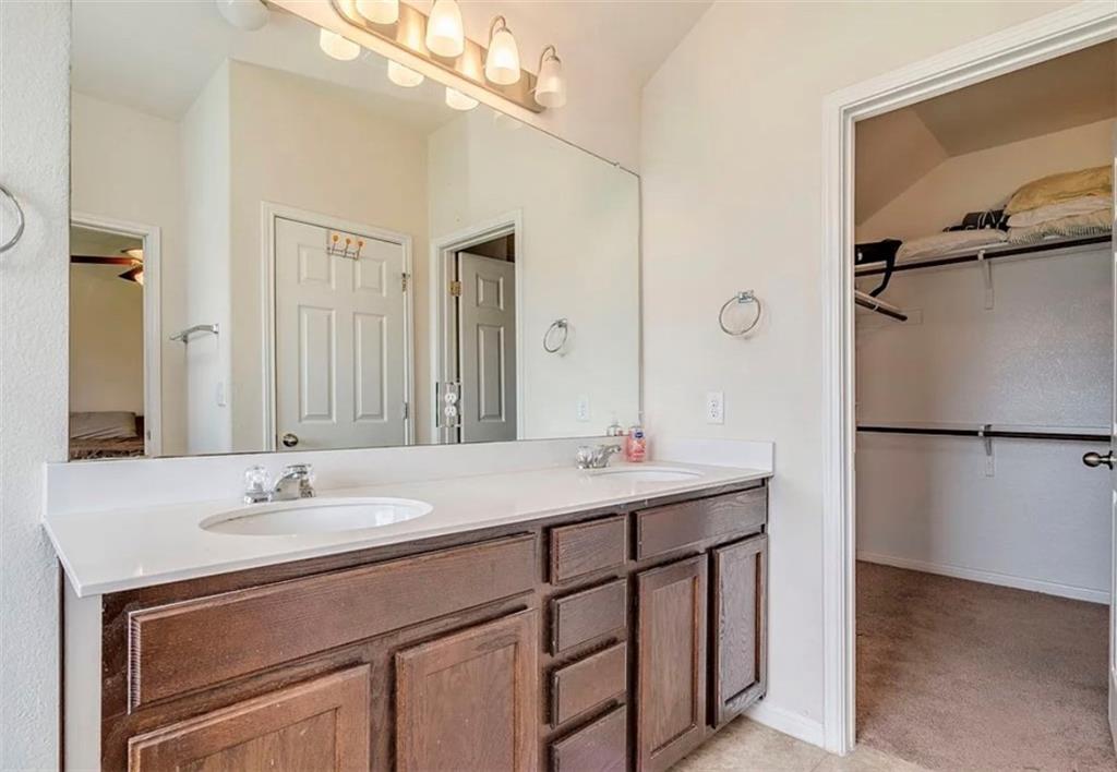 104 Beech Creek Lane Leander, TX 78641 - Photo 11 of 13 Bathroom featuring double vanity, a spacious closet, and light carpet