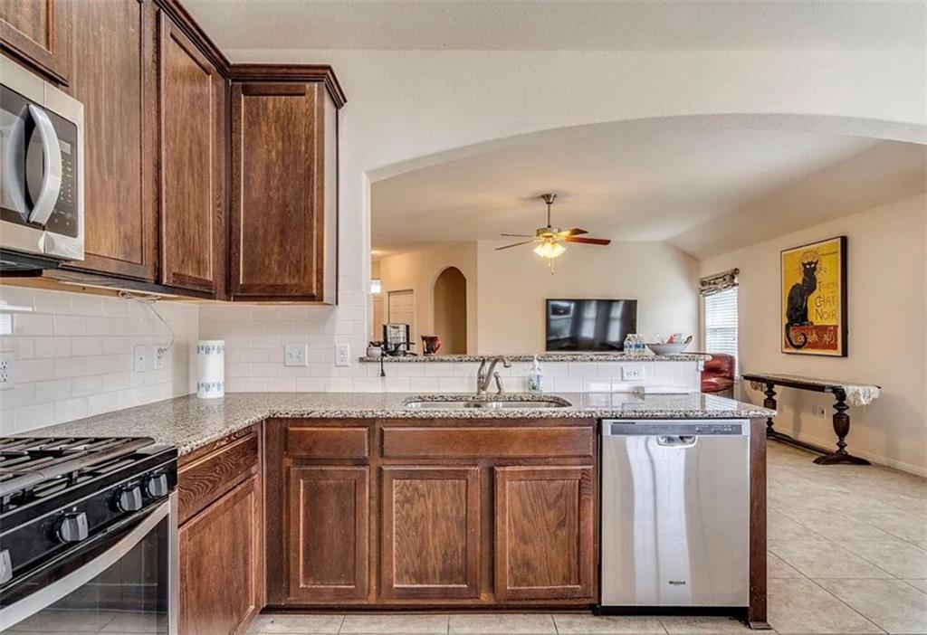104 Beech Creek Lane Leander, TX 78641 - Photo 4 of 13 Kitchen featuring arched walkways, light stone counters, stainless steel appliances, tasteful backsplash, and a peninsula