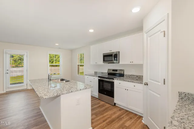 a kitchen with granite countertop a stove top oven sink and cabinets