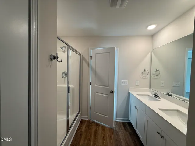 a bathroom with a double vanity sink a mirror and shower