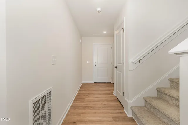 a view of a hallway with wooden floor and staircase