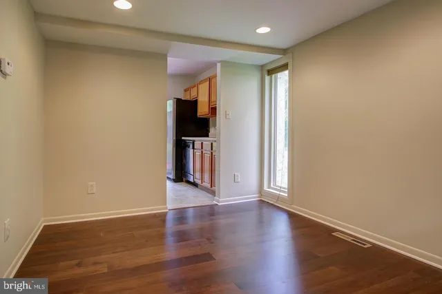 an empty room with wooden floor fireplace and windows
