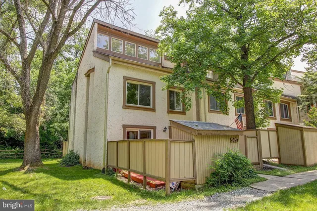 a view of a house with large windows and a yard with plants and large trees