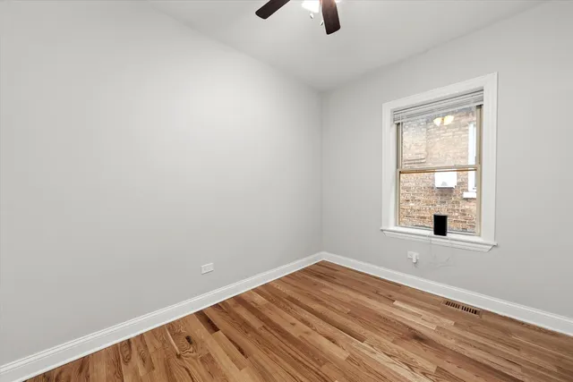 an empty room with a window and a ceiling fan