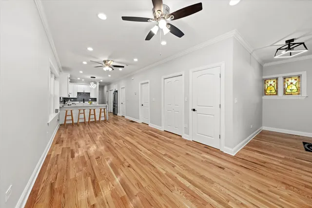 a view of a room with wooden floor a ceiling fan and kitchen space