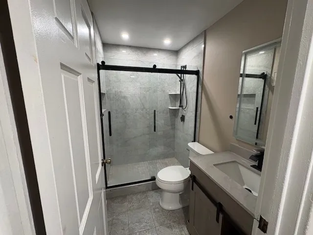 a bathroom with a granite countertop sink toilet and shower