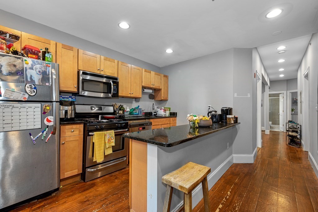 16 Sewall Street Boston, MA 02120 - Photo 22 of 42 a kitchen with stainless steel appliances granite countertop a stove top oven a sink a dining table and chairs with wooden floor