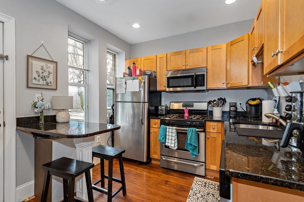 16 Sewall Street Boston, MA 02120 - Photo 7 of 42 a kitchen with stainless steel appliances granite countertop a refrigerator a stove top oven a sink dishwasher and dining table with wooden floor