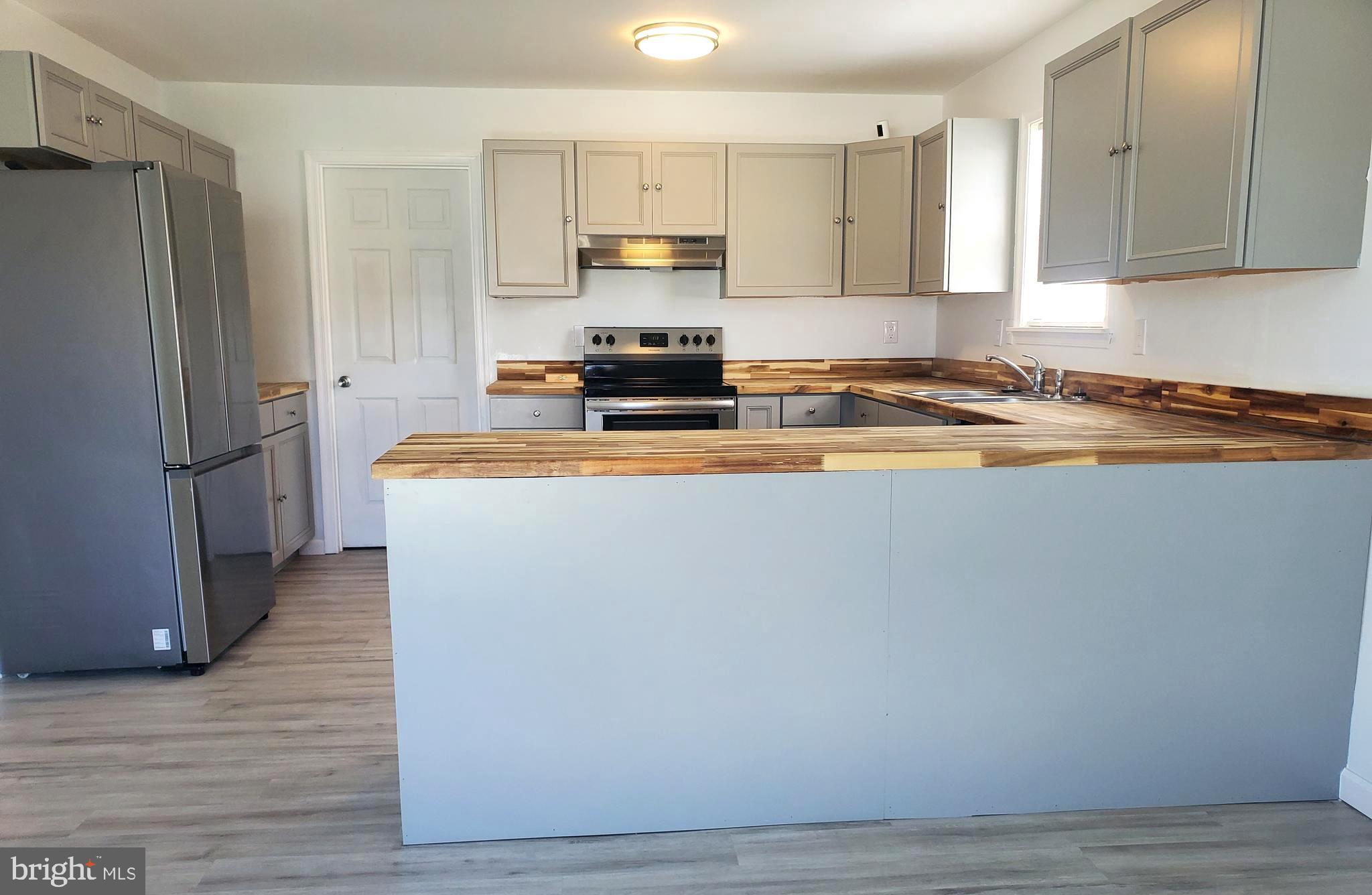 112 Holmes Street Dover, DE 19901 - Photo 3 of 24 a kitchen with stainless steel appliances granite countertop a refrigerator a stove a sink and a granite counter tops with wooden floors