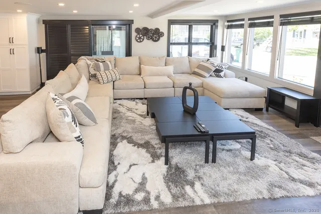 a living room with furniture wooden floor and a large window