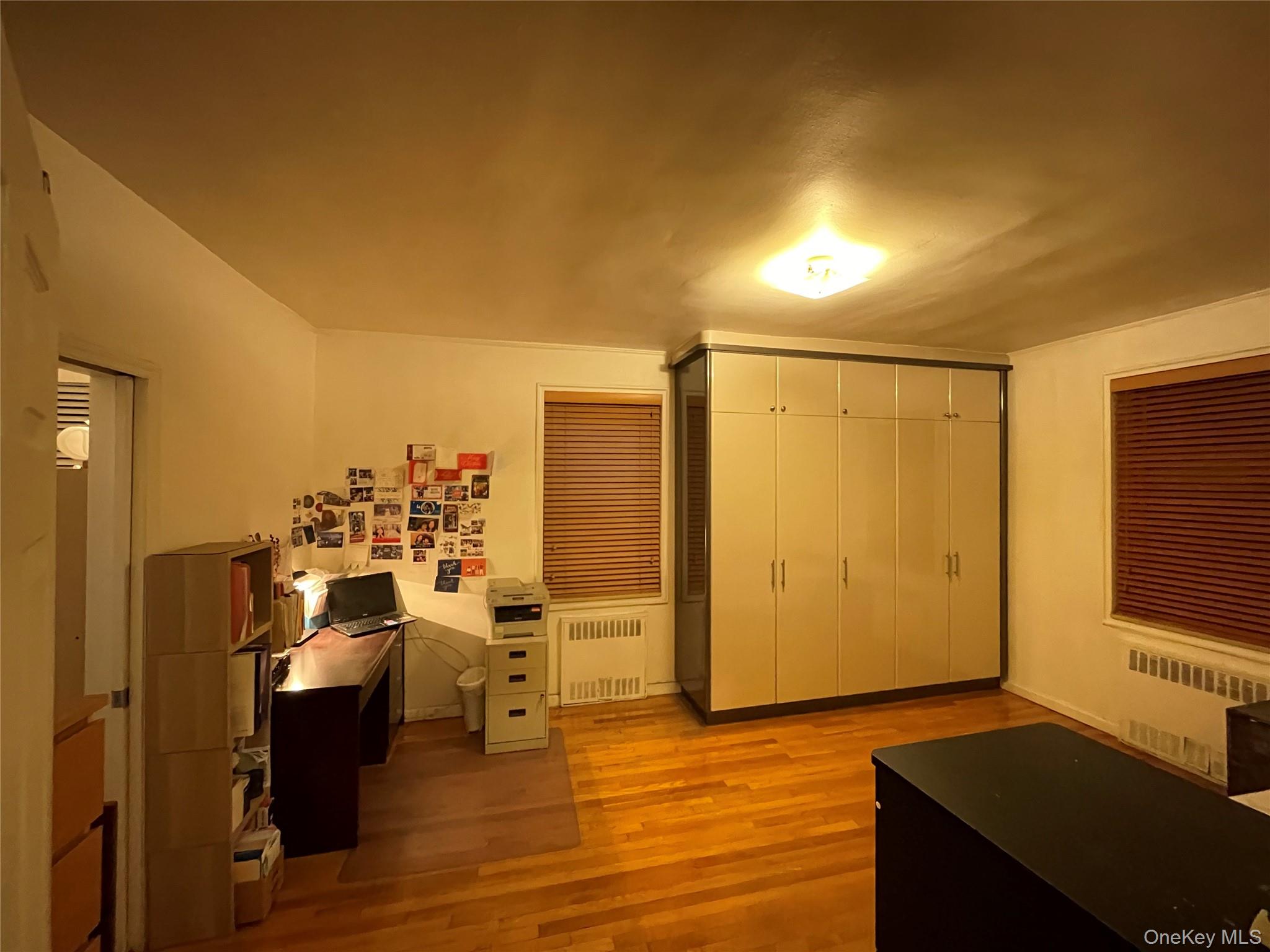 63-60 102nd Street, Unit D7 Queens, NY 11374 - Photo 11 of 41 Home office featuring radiator heating unit and light wood-style flooring