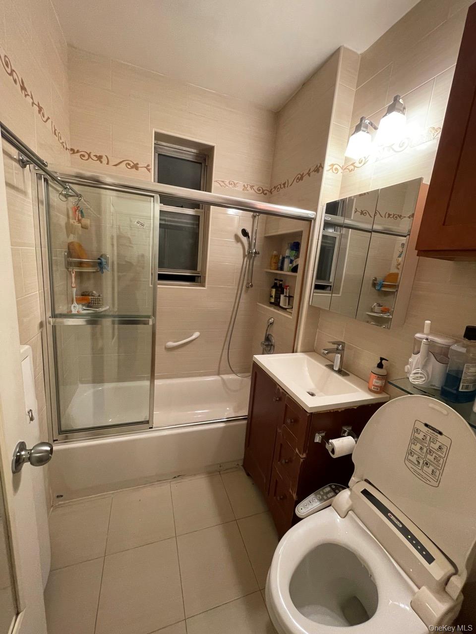 63-60 102nd Street, Unit D7 Queens, NY 11374 - Photo 31 of 41 Full bathroom featuring combined bath / shower with glass door, vanity, light tile patterned flooring, tile walls, and tasteful backsplash