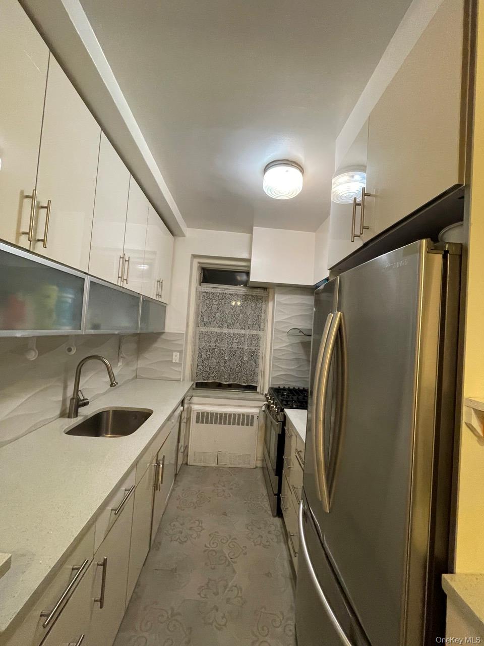 63-60 102nd Street, Unit D7 Queens, NY 11374 - Photo 5 of 41 Kitchen featuring stainless steel appliances, light stone countertops, radiator, modern cabinets, and backsplash