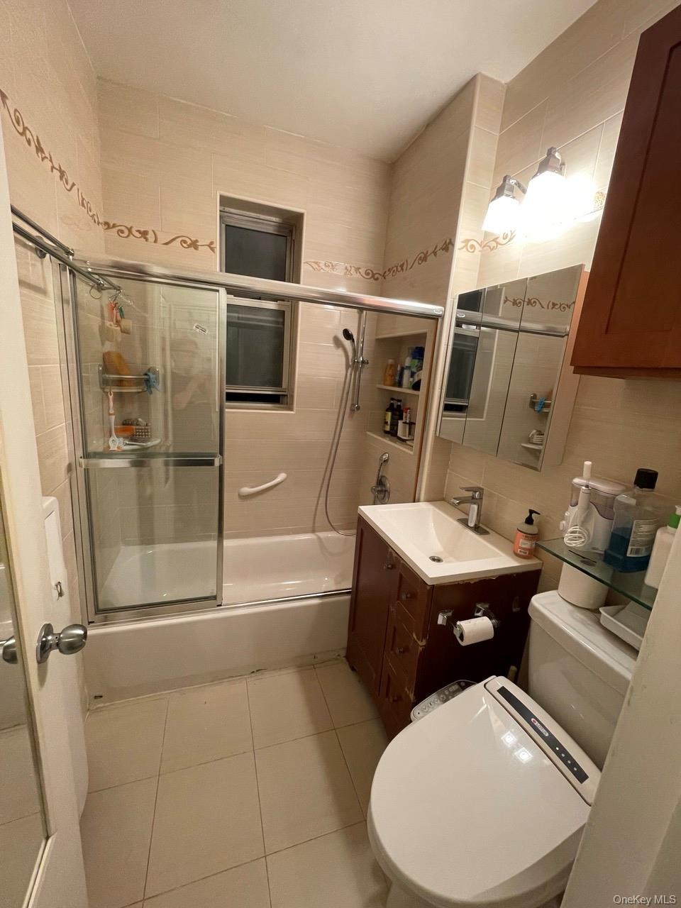 63-60 102nd Street, Unit D7 Queens, NY 11374 - Photo 8 of 41 Bathroom with enclosed tub / shower combo, light tile patterned floors, vanity, tile walls, and decorative backsplash