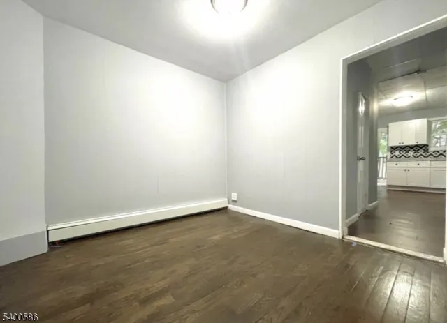 an empty room with wooden floor cabinet and windows