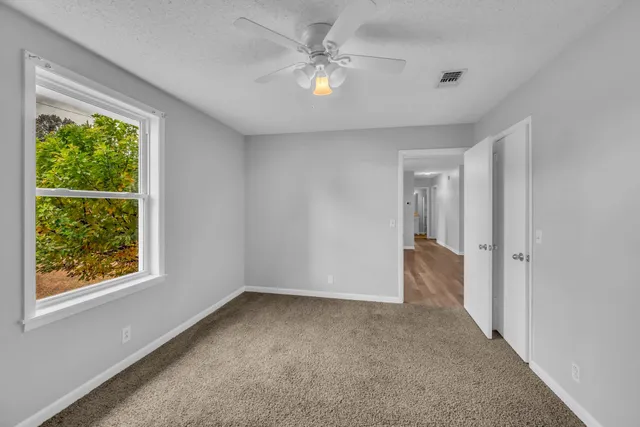 an empty room with a window and a ceiling fan