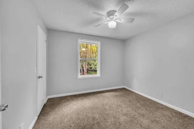 an empty room with a window and a fan