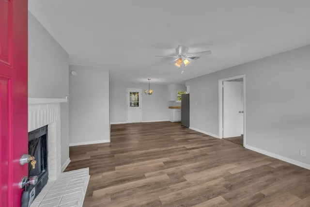 a view of an empty room with wooden floor and a fireplace