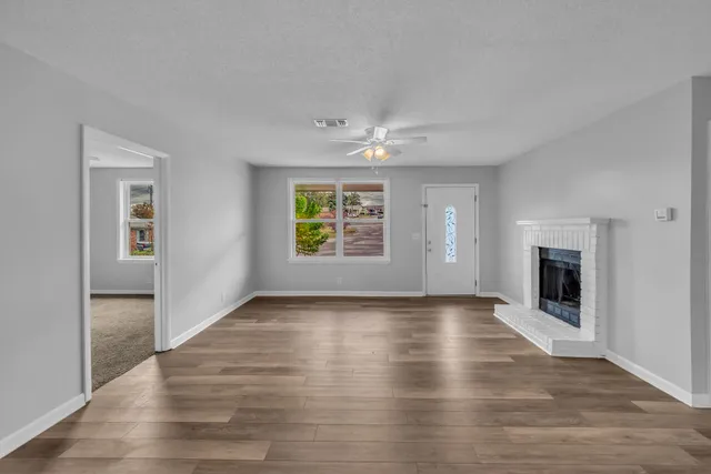 an empty room with windows and a fireplace