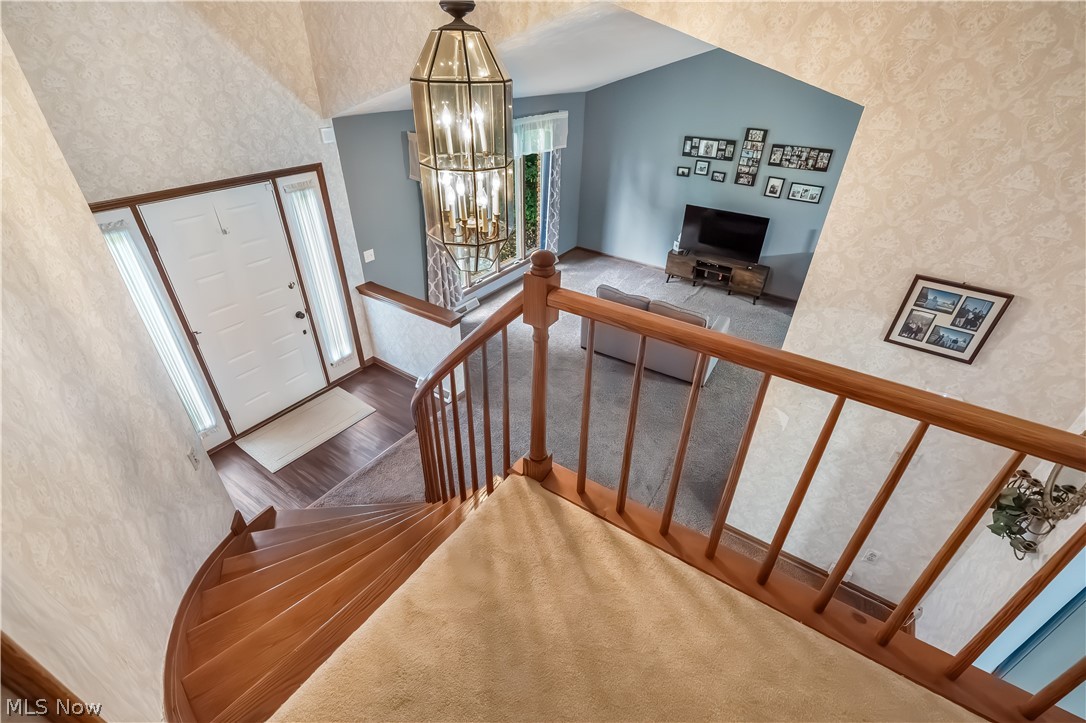 4922 South Ridge Road East Geneva, OH 44041 - Photo 4 of 46 Sweeping view from the upper landing highlighting the curved staircase, natural wood railing,
hanging light fixture, and open sightlines to the light-filled entry below.