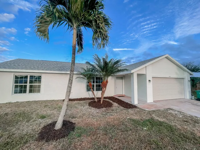 a view of a house with a yard and palm trees