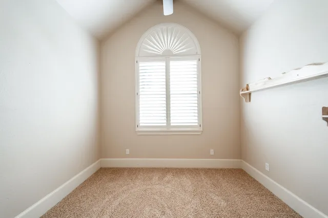 an empty room with a window and a chandelier fan