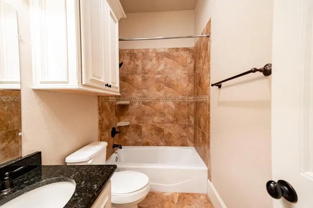 a bathroom with a granite countertop sink toilet a mirror and shower