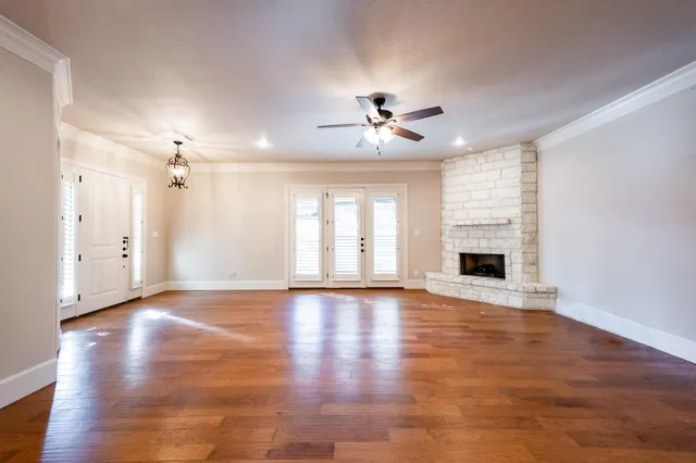 a view of an empty room with a window and wooden floor